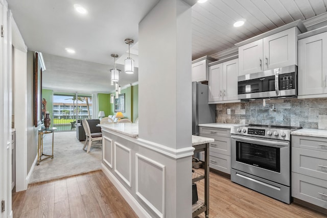 kitchen with tasteful backsplash, gray cabinets, light colored carpet, decorative light fixtures, and stainless steel appliances