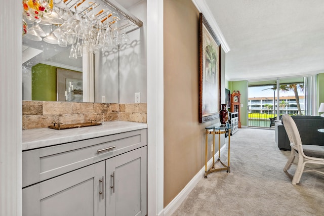 bar with gray cabinets, crown molding, light colored carpet, and a notable chandelier