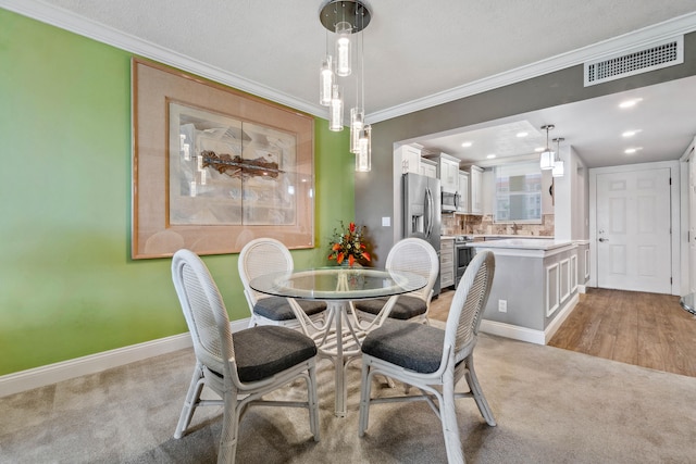 carpeted dining room featuring crown molding and a textured ceiling