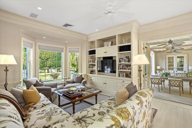 living room featuring built in features, light hardwood / wood-style floors, french doors, and ornamental molding