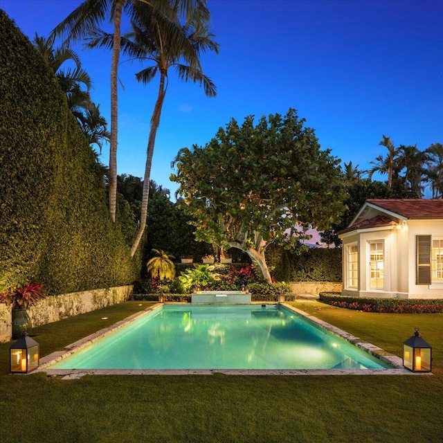 pool at dusk featuring a yard