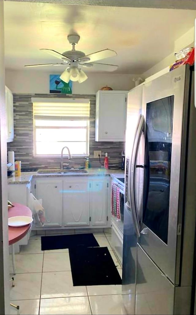 kitchen featuring white cabinetry, tasteful backsplash, stainless steel fridge, and light tile floors