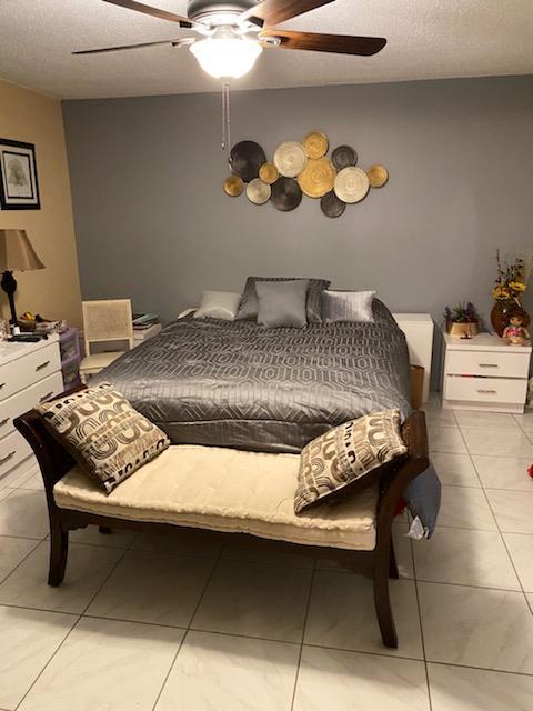 tiled bedroom featuring ceiling fan and a textured ceiling