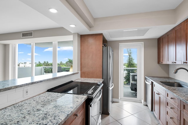 kitchen with appliances with stainless steel finishes, sink, light tile patterned floors, and light stone countertops