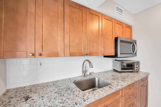 kitchen with light stone countertops, sink, and backsplash