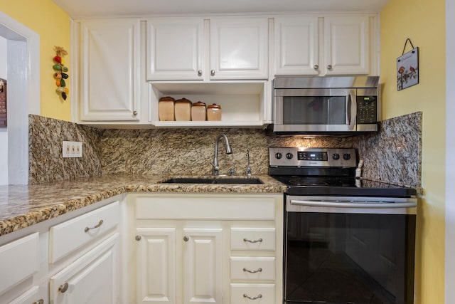 kitchen with sink, backsplash, white cabinetry, and stainless steel appliances