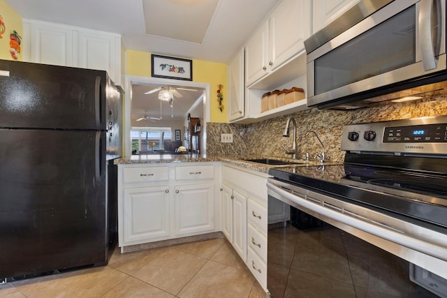 kitchen with light tile patterned floors, stone counters, appliances with stainless steel finishes, tasteful backsplash, and white cabinets