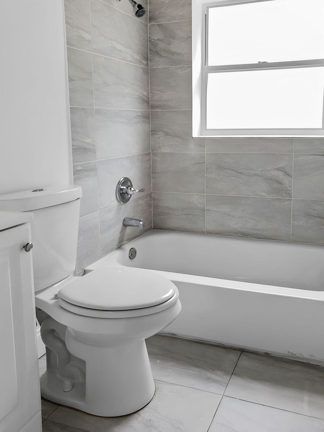 full bathroom with tile floors, tiled shower / bath, vanity, and toilet