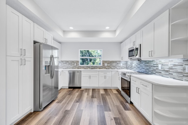 kitchen featuring backsplash, stainless steel appliances, light hardwood / wood-style floors, white cabinets, and sink