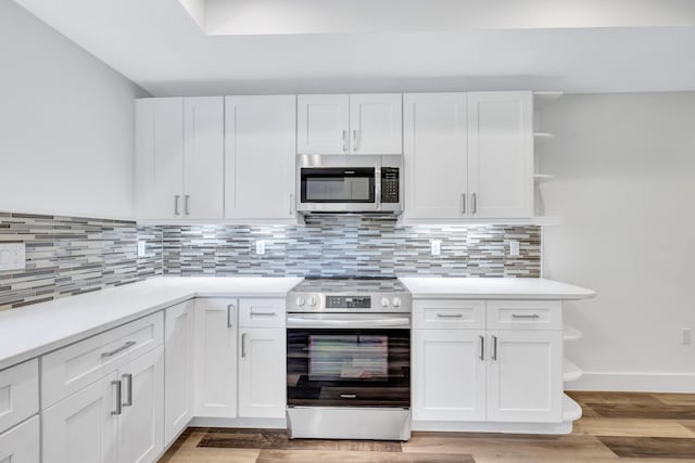 kitchen with tasteful backsplash, stainless steel appliances, hardwood / wood-style flooring, and white cabinetry