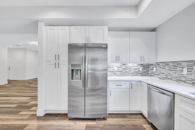 kitchen featuring backsplash, appliances with stainless steel finishes, wood-type flooring, and white cabinetry