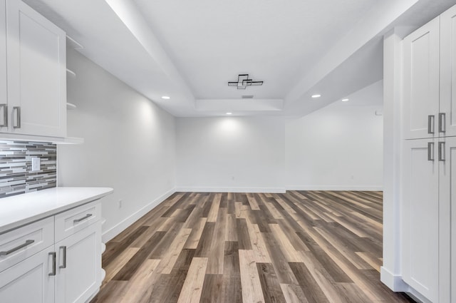 unfurnished dining area with dark hardwood / wood-style flooring and a tray ceiling