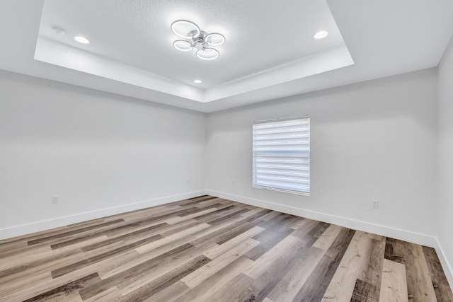 empty room featuring wood-type flooring and a tray ceiling