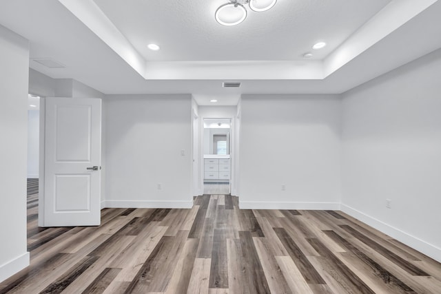 spare room featuring a textured ceiling, hardwood / wood-style floors, and a tray ceiling