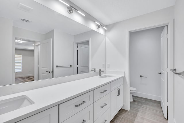 bathroom featuring large vanity, tile floors, toilet, and double sink