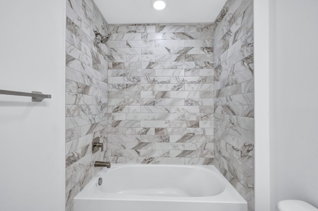 bathroom featuring tiled shower / bath combo and toilet