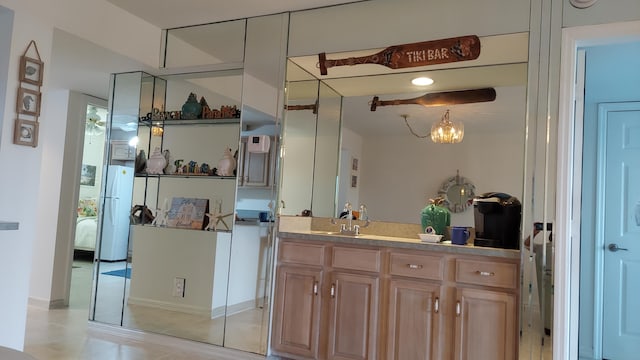 kitchen with white fridge, light brown cabinetry, a notable chandelier, and light tile flooring