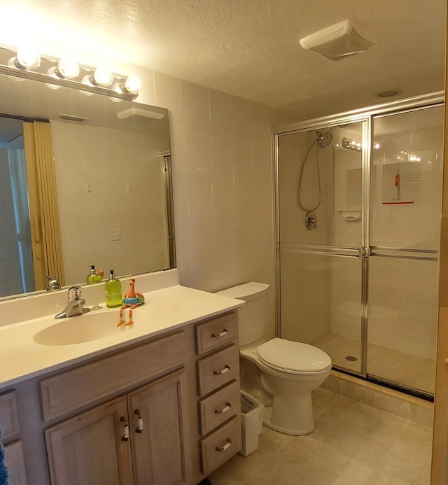 bathroom with tile flooring, large vanity, a textured ceiling, toilet, and a shower with door