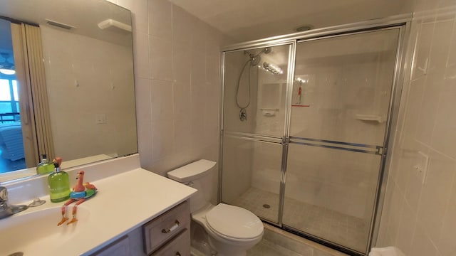 bathroom featuring vanity, toilet, tile walls, and a shower with door