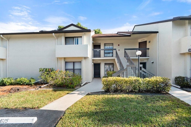 multi unit property featuring a balcony and a front lawn