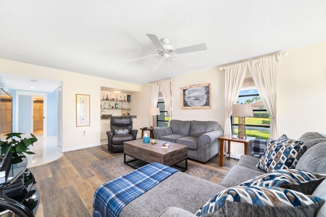 living room with ceiling fan, a textured ceiling, and hardwood / wood-style flooring