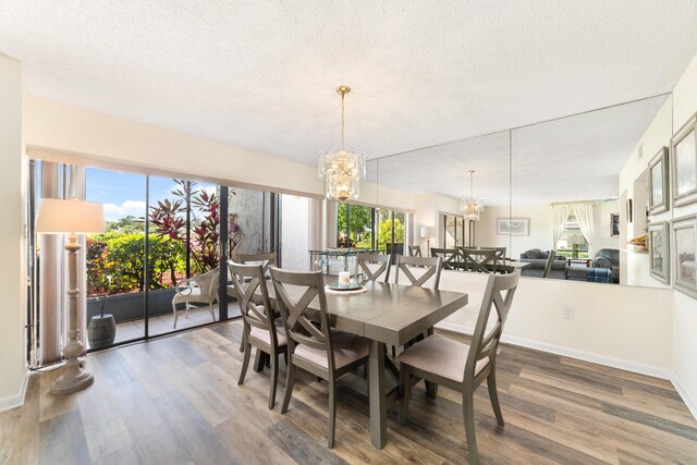 dining room featuring plenty of natural light, an inviting chandelier, a textured ceiling, and dark wood-type flooring