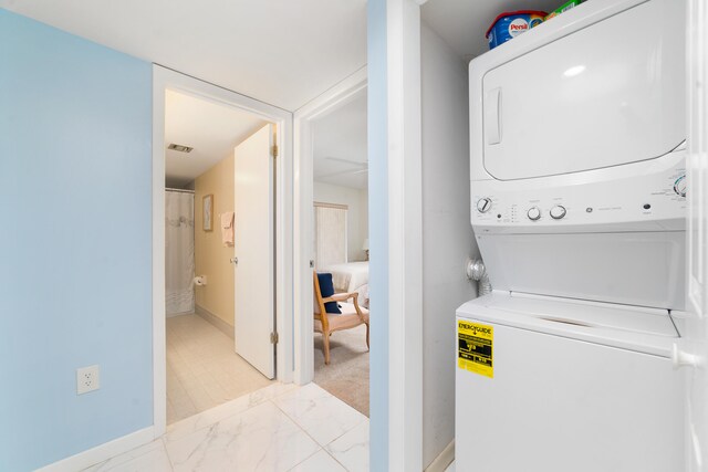 laundry area featuring light tile floors and stacked washer / drying machine