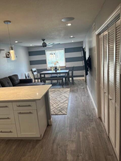 kitchen featuring ceiling fan, pendant lighting, dark wood-type flooring, and white cabinetry