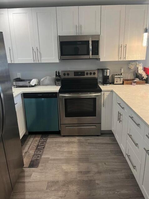 kitchen featuring white cabinets, appliances with stainless steel finishes, and hardwood / wood-style flooring