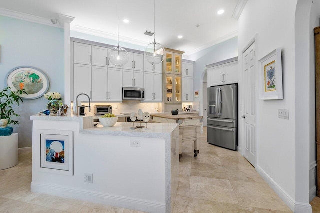 kitchen featuring decorative light fixtures, light stone counters, ornamental molding, and stainless steel appliances