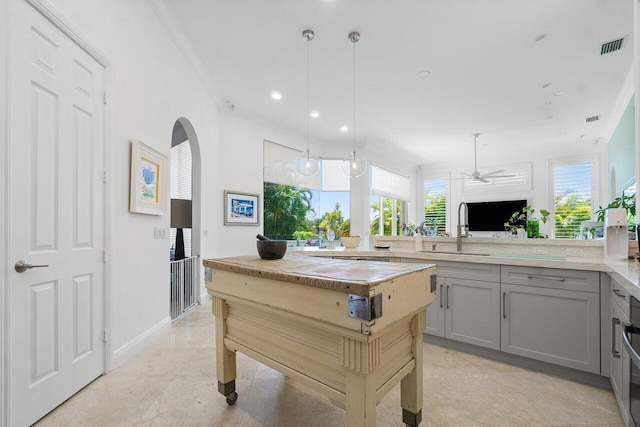 kitchen with gray cabinets, decorative light fixtures, sink, ornamental molding, and a center island