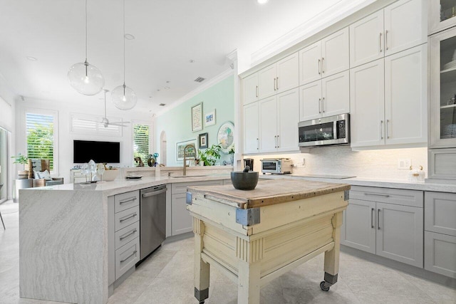 kitchen featuring a center island, decorative backsplash, sink, appliances with stainless steel finishes, and gray cabinetry