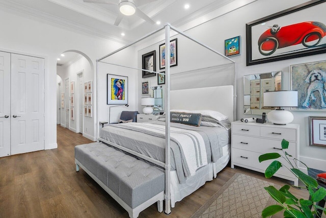 bedroom featuring ceiling fan, a closet, dark hardwood / wood-style flooring, and crown molding