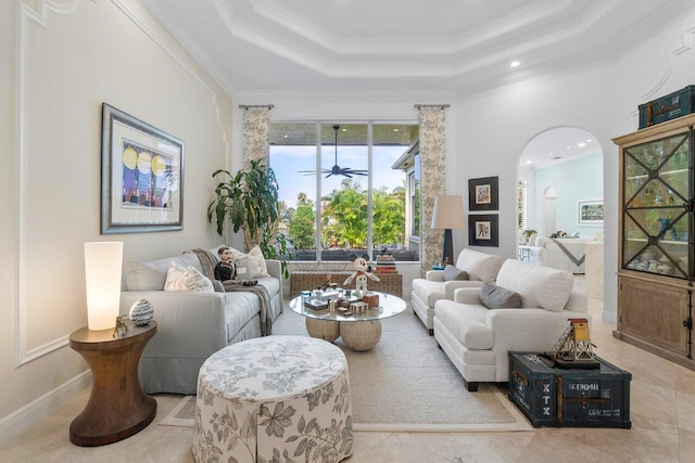 living room with ceiling fan, ornamental molding, a towering ceiling, and a raised ceiling