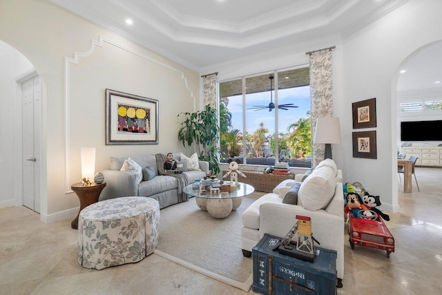 living room with ceiling fan, a tray ceiling, crown molding, and a high ceiling