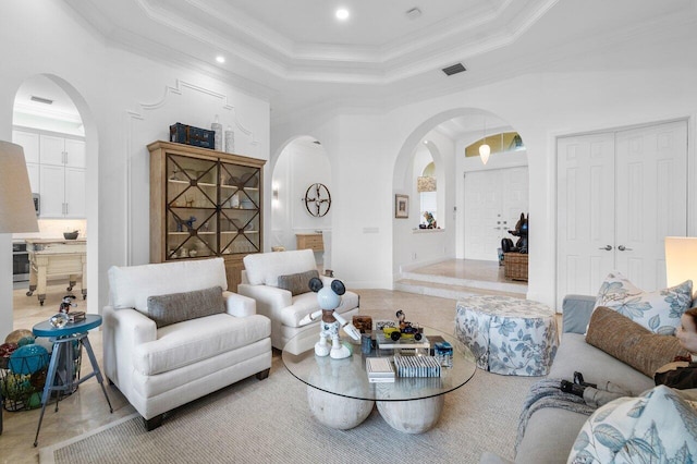 living room featuring a raised ceiling, ornamental molding, and a towering ceiling