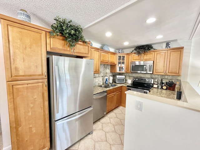 kitchen with stainless steel appliances, sink, light tile floors, tasteful backsplash, and a textured ceiling