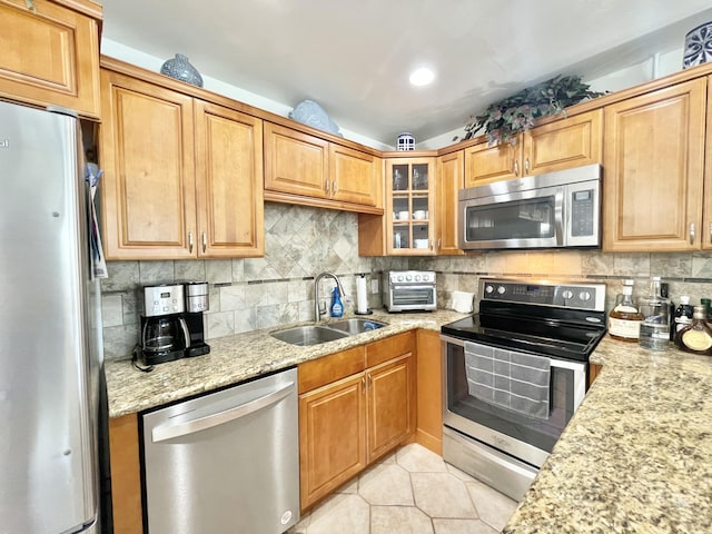 kitchen featuring stainless steel appliances, light tile flooring, tasteful backsplash, light stone counters, and sink