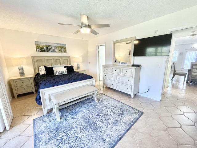 bedroom featuring light tile floors, ceiling fan, and a textured ceiling