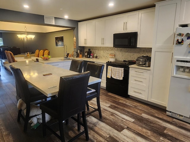 kitchen featuring tasteful backsplash, white cabinetry, dark wood-type flooring, a chandelier, and black appliances