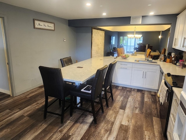 kitchen with a chandelier, kitchen peninsula, white cabinets, and dark hardwood / wood-style floors