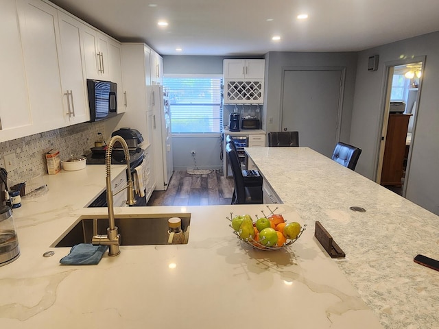 kitchen featuring dark hardwood / wood-style flooring, backsplash, white cabinetry, and light stone counters