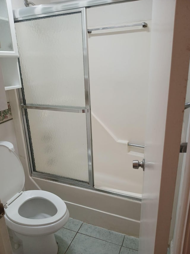 bathroom featuring tile flooring, toilet, and shower / bath combination with glass door