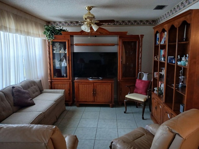 tiled living room with ceiling fan and a textured ceiling