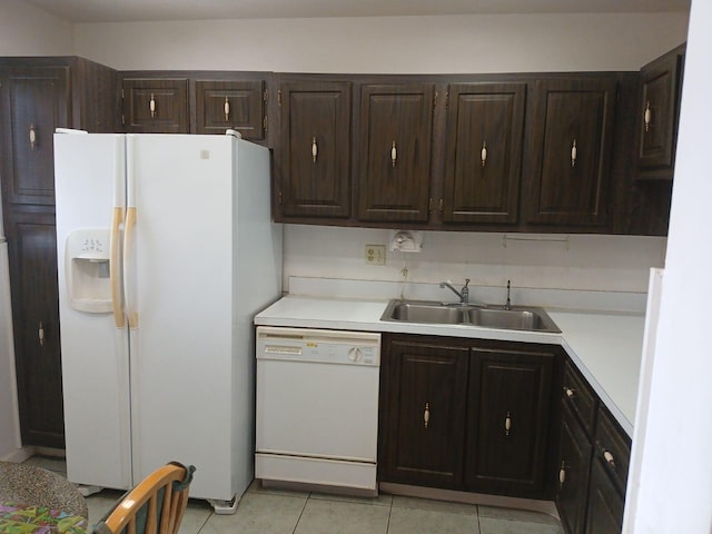 kitchen featuring light tile floors, dark brown cabinets, white appliances, and sink