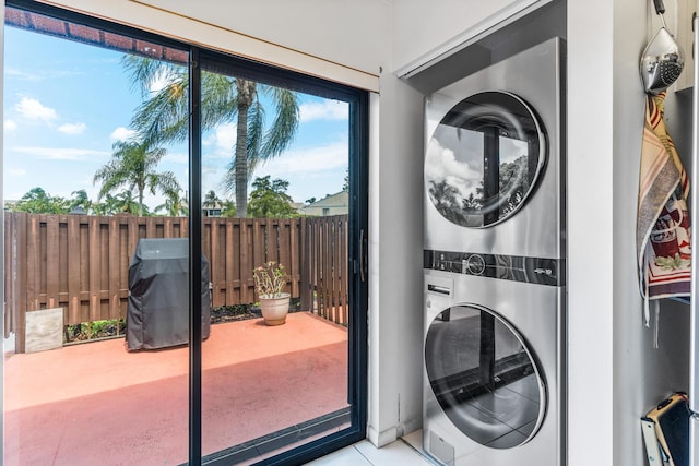 laundry room featuring stacked washer and clothes dryer and light tile patterned flooring