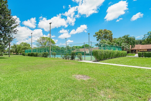 view of property's community with tennis court and a yard