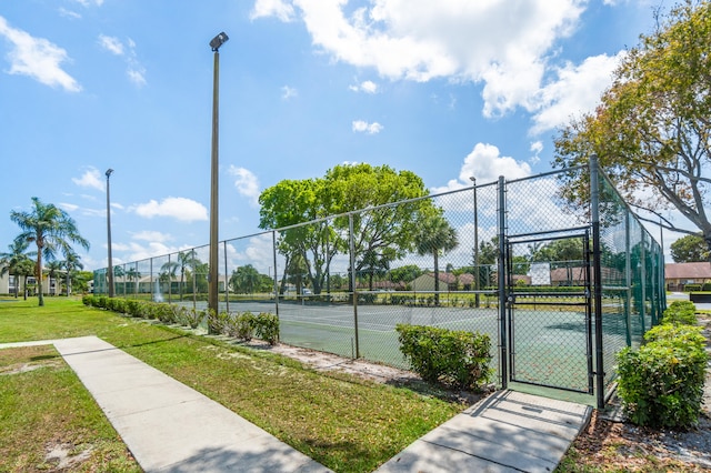 view of tennis court featuring a lawn