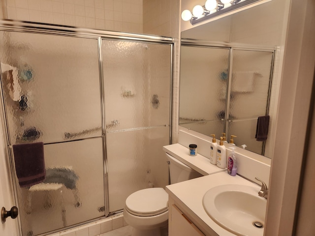 bathroom featuring toilet, a shower with shower door, and vanity