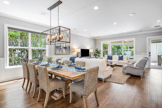 dining space featuring hardwood / wood-style flooring, an inviting chandelier, and crown molding